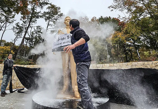 경북 경산시 영남대학교에서 10일 영남대 민주동문회원들이 대학 내 설치된 박정희 동상에 밀가루를 뿌리고 있다.   [연합뉴스]